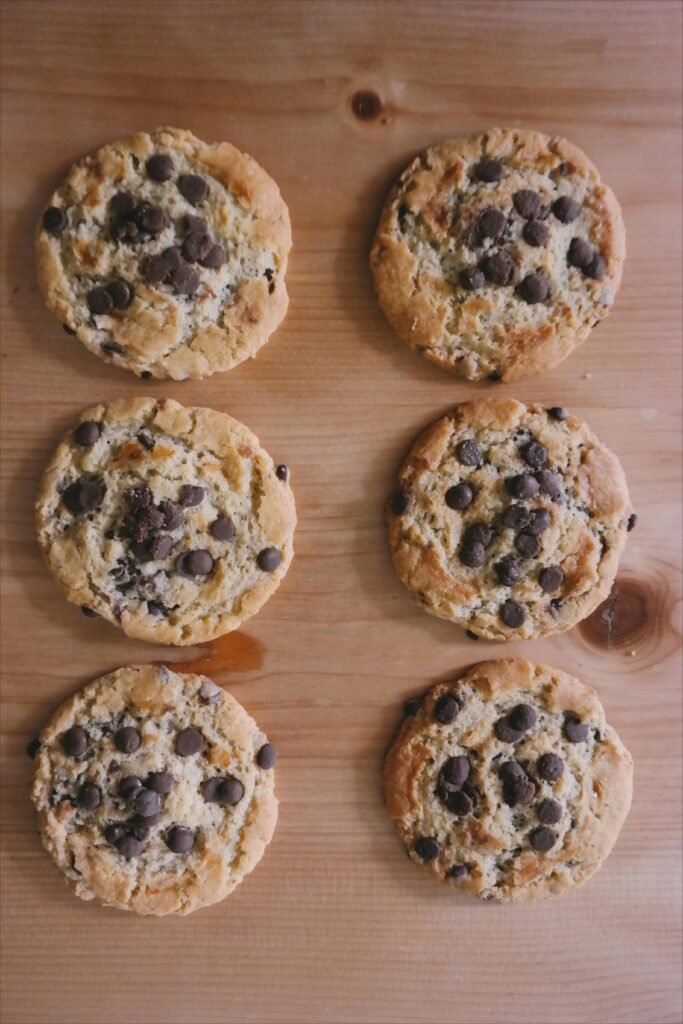 Foods That Are Toxic To DOGS! - BE INFORMED 23 Freshly baked chocolate chip cookies arranged on a wooden surface, showcasing their tasty appeal.