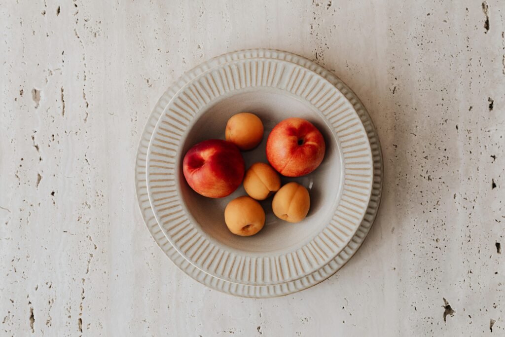 Foods That Are Toxic To DOGS! - BE INFORMED 20 Overhead view of ripe apricots and peaches on a ceramic plate, ideal for food photography.
